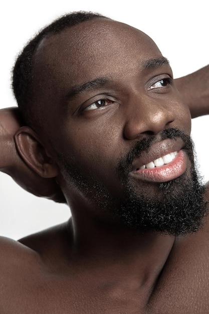 Portrait of a young naked happy smiling african man at studio. High Fashion male model posing and isolated on white background