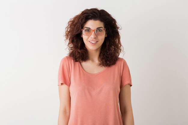 Portrait of young natural smiling hipster pretty woman with curly hairstyle in pink shirt posing wearing glasses isolated on white studio background