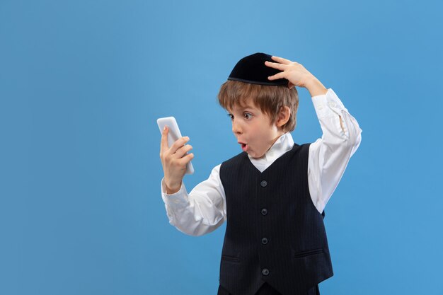 Portrait of a young orthodox jewish boy isolated on blue studio