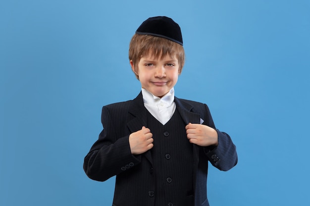 Free photo portrait of a young orthodox jewish boy isolated on blue studio