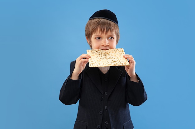 Free photo portrait of a young orthodox jewish boy isolated on blue wall meeting the passover