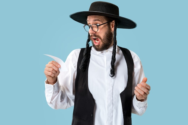 Portrait of a young orthodox jewish man with bet slip at studio. Holiday, celebration, judaism, betting concept.