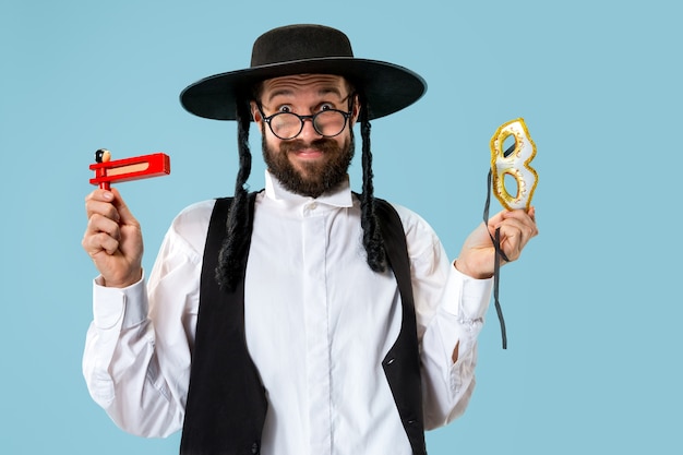 Free photo portrait of a young orthodox jewish man with wooden grager ratchet during festival purim