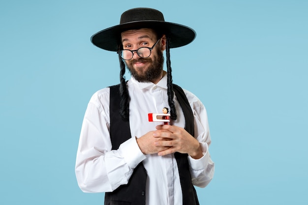 Free photo portrait of a young orthodox jewish man with wooden grager ratchet during festival purim.