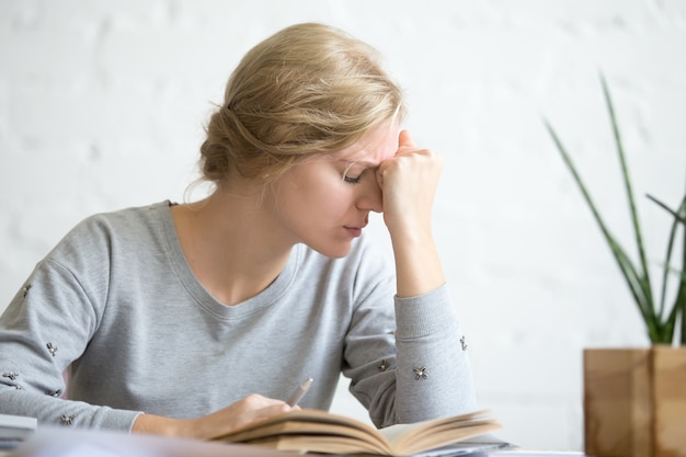 Portrait of a young overworked student girl sitting at the table