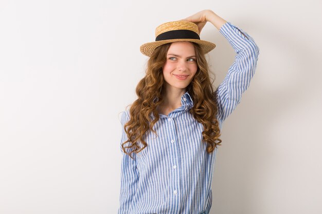 Portrait of young pretty woman with straw hat jeans blue cotton shirt posing on white wall