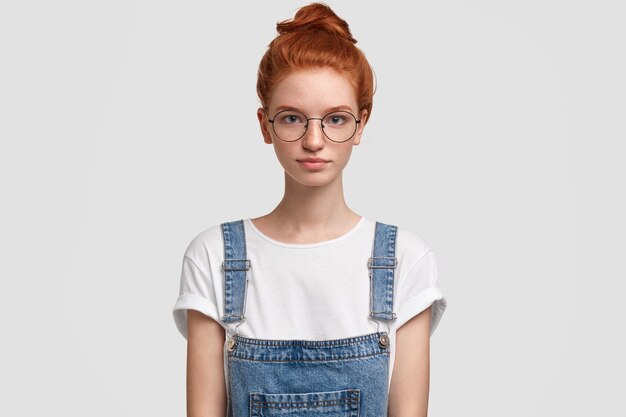 Portrait of young red-haired woman wearing denim overalls