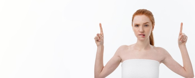 Free photo portrait of young redhead female with perfect freckled skin showing something interesting at copy sp