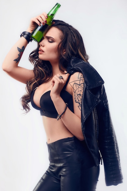 Free photo portrait of young sexy woman with long hair in leather jacket holding bottle of beer