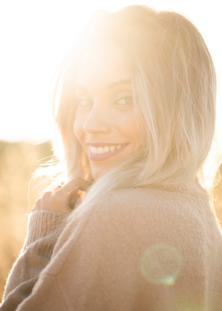 Free photo portrait of young smiling woman in sunlight looking at camera