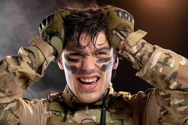 Portrait of young soldier in camouflage on a dark wall