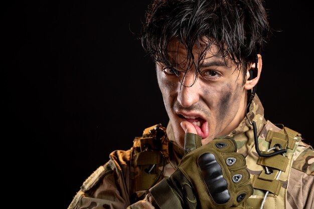 Portrait of young soldier in uniform on the dark wall