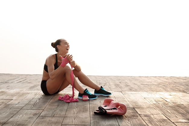 Portrait of young sportive beautiful girl preparing for boxing training at seaside.