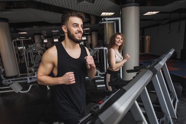 Portrait of young sports couple making cardio workout in modern gym