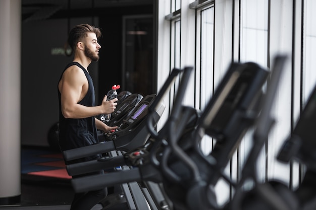 Free Photo portrait of young sportsman making cardio workout and drinking water in the gym