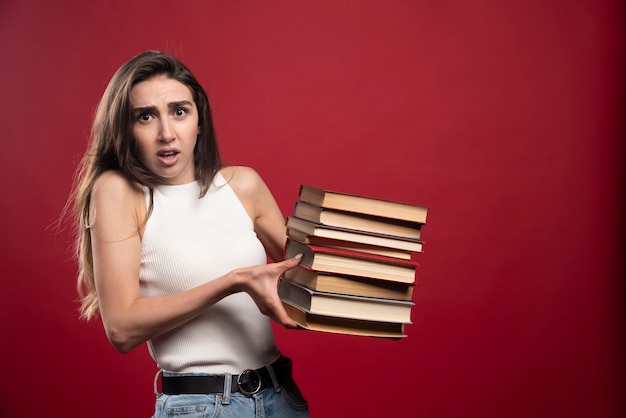 Free photo portrait of a young student woman carrying lots of books