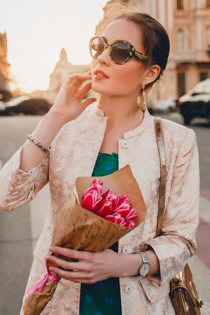 Portrait of young stylish attractive woman walking in city