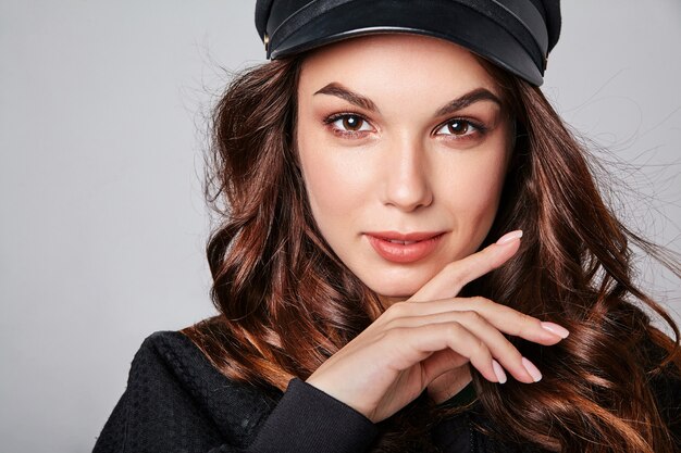 Portrait of young stylish laughing model in black casual summer clothes in cap with natural makeup on gray