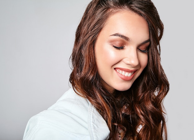 Portrait of young stylish laughing model in colorful casual summer clothes with natural makeup on gray