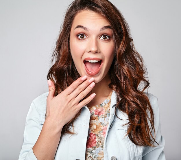 Portrait of young stylish laughing model in colorful casual summer clothes with natural makeup on gray