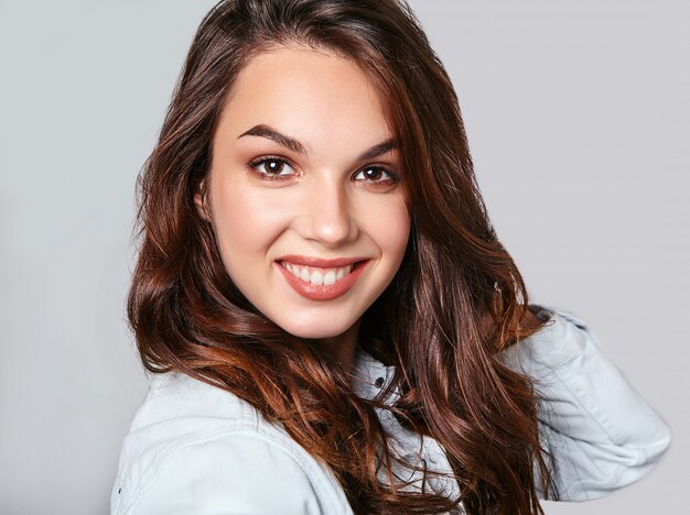 Portrait of young stylish laughing model in colorful casual summer clothes with natural makeup on gray