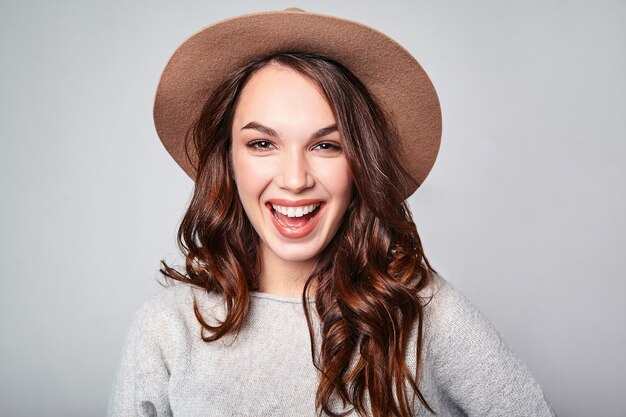 Portrait of young stylish laughing model in gray casual summer clothes in brown hat with natural makeup