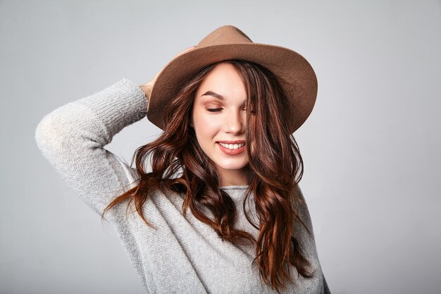 Portrait of young stylish laughing model in gray casual summer clothes in brown hat with natural makeup