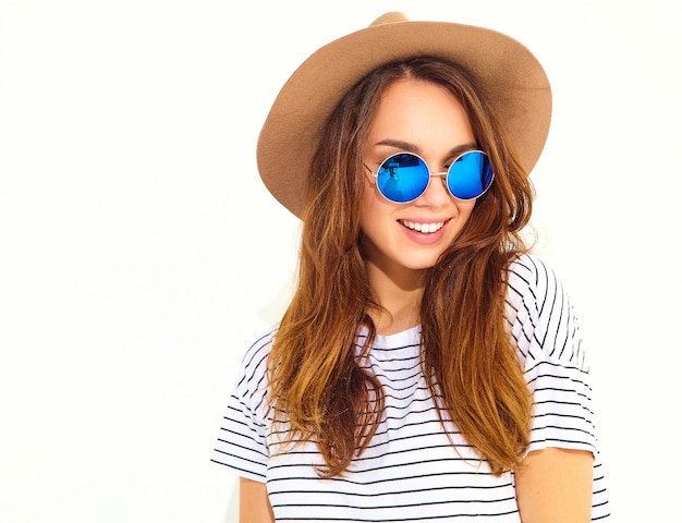 Portrait of young stylish laughing woman model in casual summer clothes in brown hat isolated on white wall