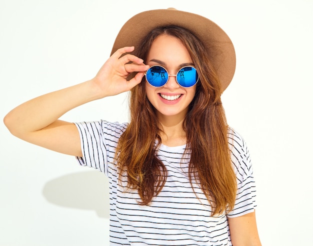 Portrait of young stylish laughing woman model in casual summer clothes in brown hat isolated on white wall