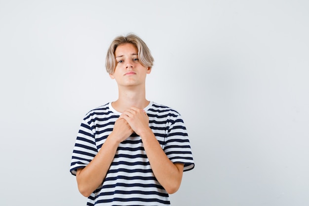 Free photo portrait of young teen boy keeping hands on chest in striped t-shirt and looking sad front view