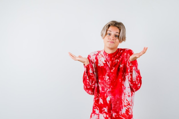 Free photo portrait of young teen boy showing helpless gesture in shirt and looking confused front view