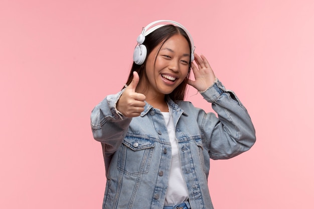 Portrait of young teenage girl with headphones giving thumbs up