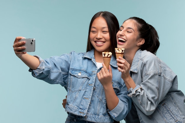 Portrait of young teenage girls taking a selfie while holding ice creams