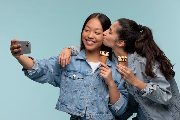 Portrait of young teenage girls taking a selfie while holding ice creams