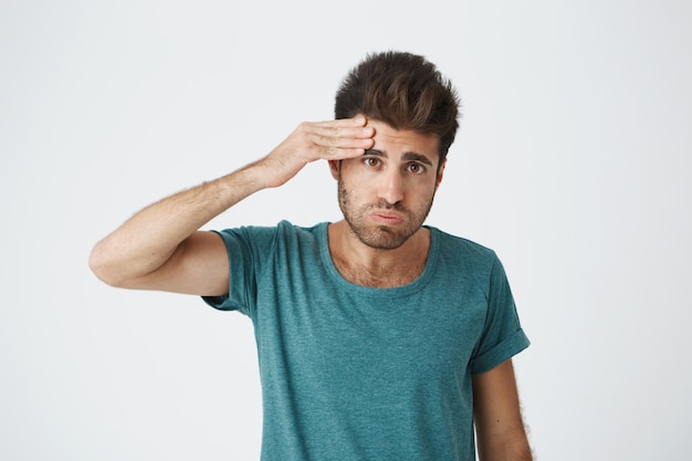 Free Photo portrait of young tired caucasian guy wearing blue tshirt wiping his forehead with hand being tired after complex training. body language.