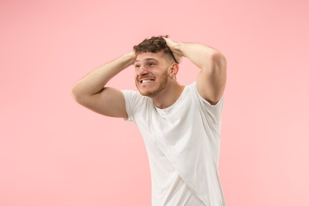 Portrait of young trendy man on pink background. Emotional expression.