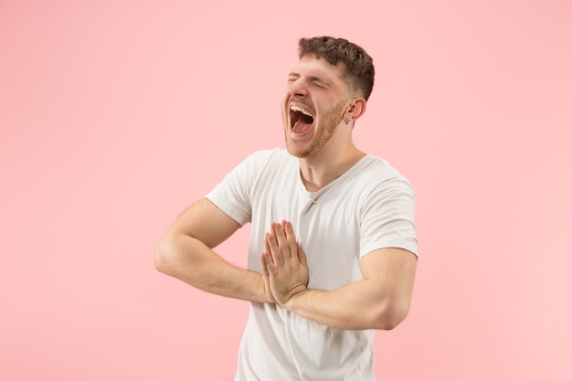 Portrait of young trendy man on pink background. Emotional expression.