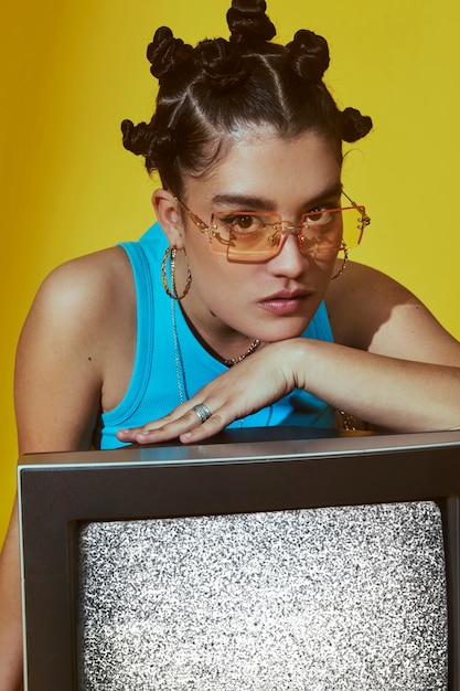 Portrait of young woman in 2000s fashion style posing with tv