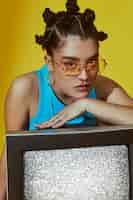 Free photo portrait of young woman in 2000s fashion style posing with tv