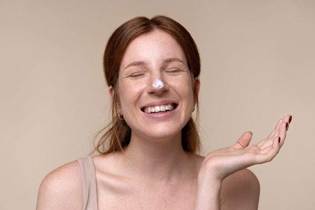 Portrait of a young woman applying moisturizer on her nose