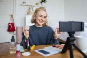 Free photo portrait of young woman beauty content creator sitting in a room in front of digital camera