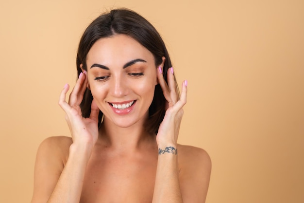 Portrait of a young woman on beige with natural makeup, with a light sensual smile, bare shoulders, beauty face, advertising of cosmetics and care