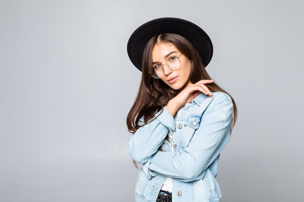 Portrait of young woman in black floppy hat isolated on white wall