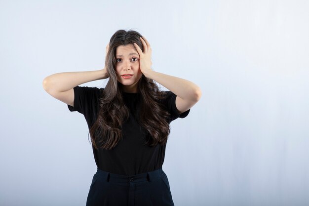 Portrait of young woman in black outfit holding her head.