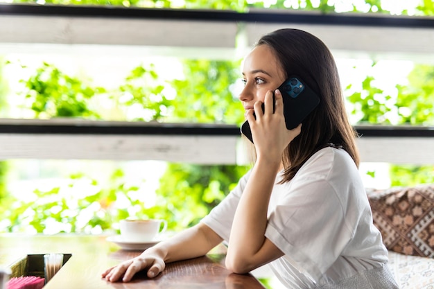 Portrait of young woman at cafe restaurant talking to the mobile phone call receiving boring talk