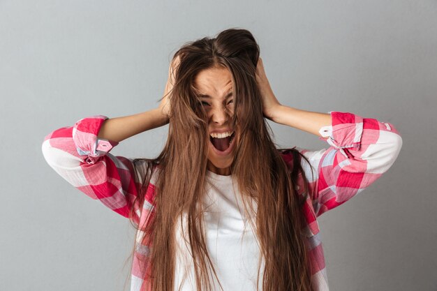 Portrait of a young woman in checkered shirt screaming