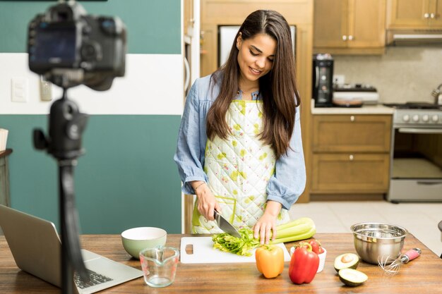 Portrait of a young woman cooking some food for her video blog at home