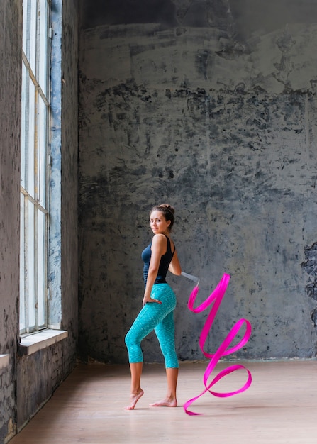 Free photo portrait of a young woman dancing with pink ribbon