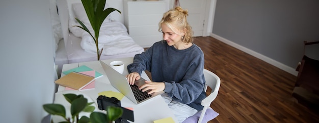 Free photo portrait of young woman distance learning working from home with laptop making notes student