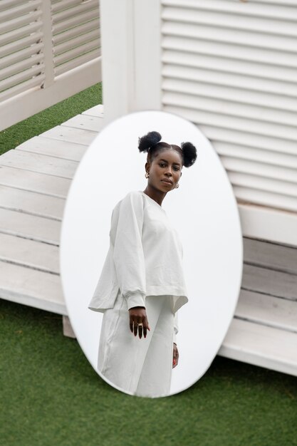 Portrait of young woman dressed in white posing in the mirror